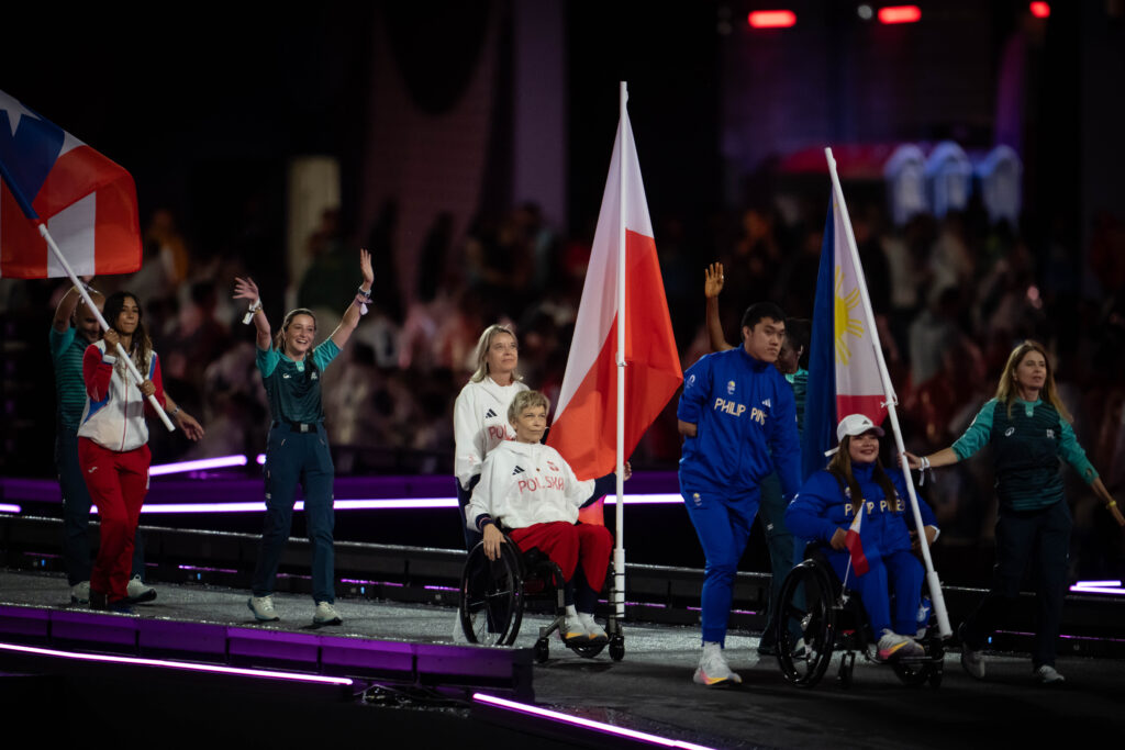 Ceremonia zamknięcia. Jadąca na wózku, pchana przez asystentkę, Dorota Bucław trzyma polską flagę