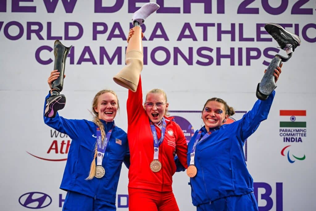 Faustyna Kotłowska i dwie Amerykanki z medalami na szyjach wznoszą do góry swoje protezy nóg
