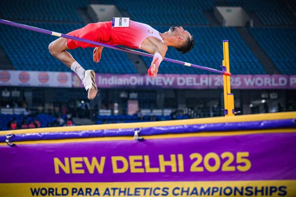 Łukasz Mamczarz podczas skoku wzwyż przelatuje nad poprzeczką na stadionie w New Delhi