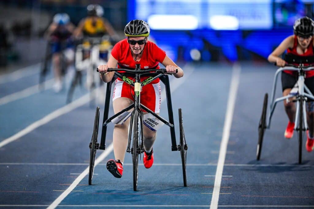 Magdalena Andruszkiewicz biegnie po lekkoatletycznej bieżni na trójkołowcu