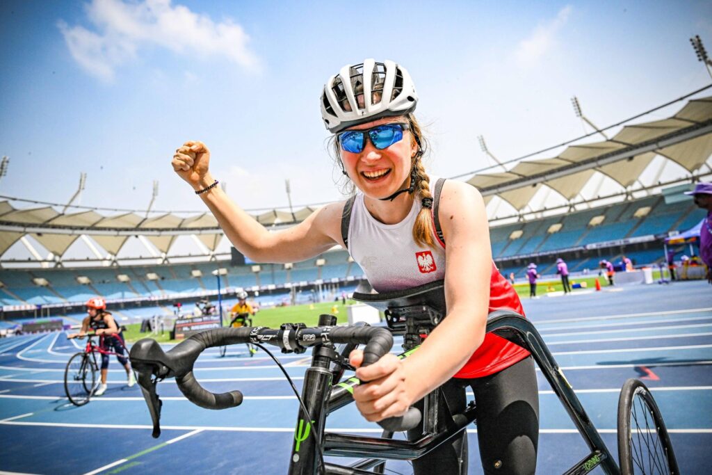 Miriam Dominikowska unosi triumfalnie pięść. Jest na stadionie, na trójkołowcu do frame runningu, czyli sprzęcie podobnym do roweru bez pedałów