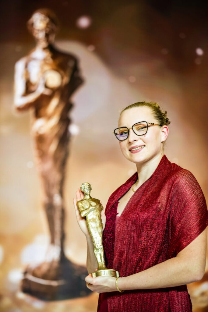 Faustyna Kotłowska w galowym stroju pozuje do zdjęcia ze statuetką Guttmanna