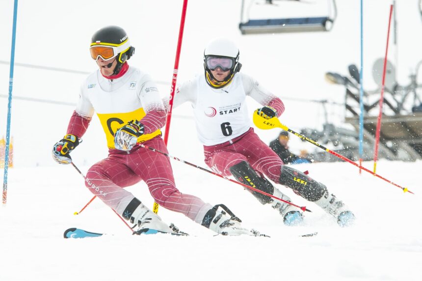 Michał Gołaś tuż za przewodnikiem pędzą po stoku narciarskim, mijając tyczkę slalomową