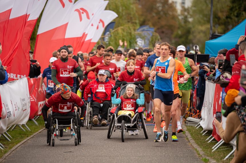 Duża grupa ludzi startuje do biegu. Część z nich to osoby na wózkach, są też dzieci