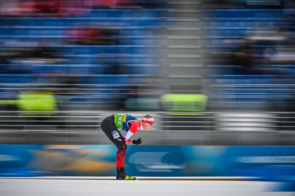 Witold Skupień schylony jedzie na nartach po śniegu