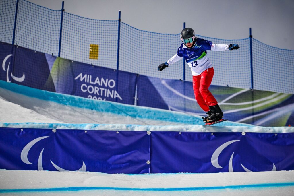 Natalia Siuba-Jarosz na desce snowboardowej skacze z niewielkiego uskoku na trasie slalomu