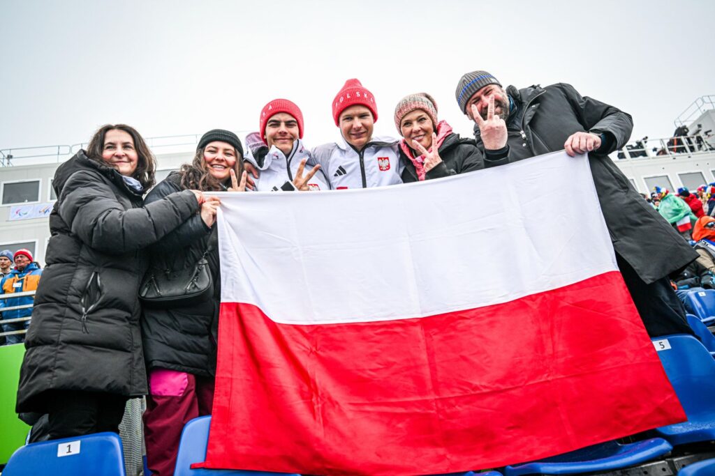Michał Gołaś i Kacper Walas razem ze swoimi rodzinami pozują do zdjęcia z polską flagą