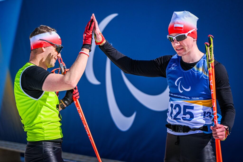 Błażej Bieńko i Michał Lańda w strojach narciarskich przybijają piątkę na mecie