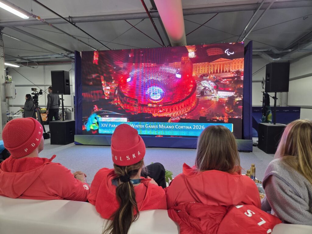 Reprezentanci Polski siedzą przed dużym ekranem telewizyjnym