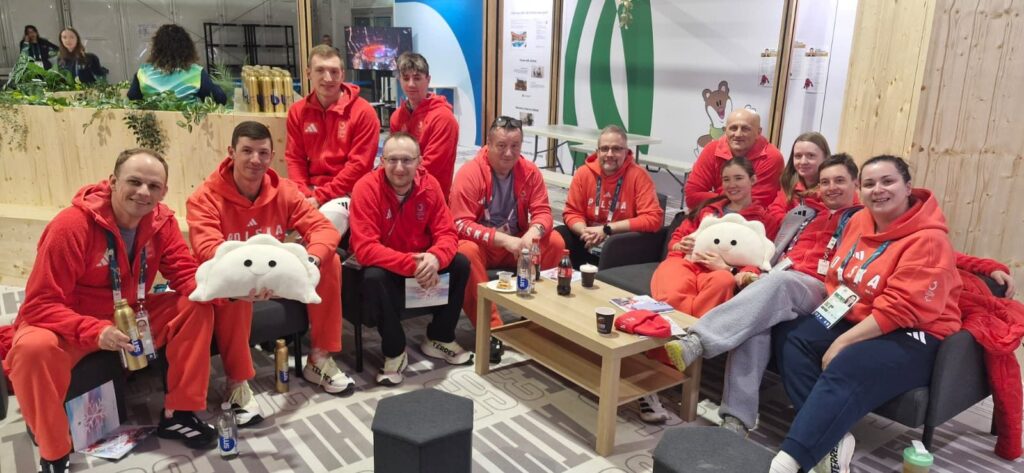 Reprezentanci Polski siedzą na kanapach i krzesłach, pozując do zdjęcia