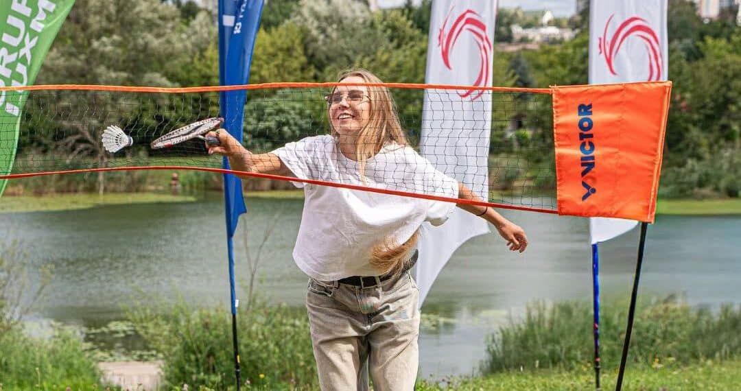 Kobieta odbija nad siatką lotkę rakietką do badmintona